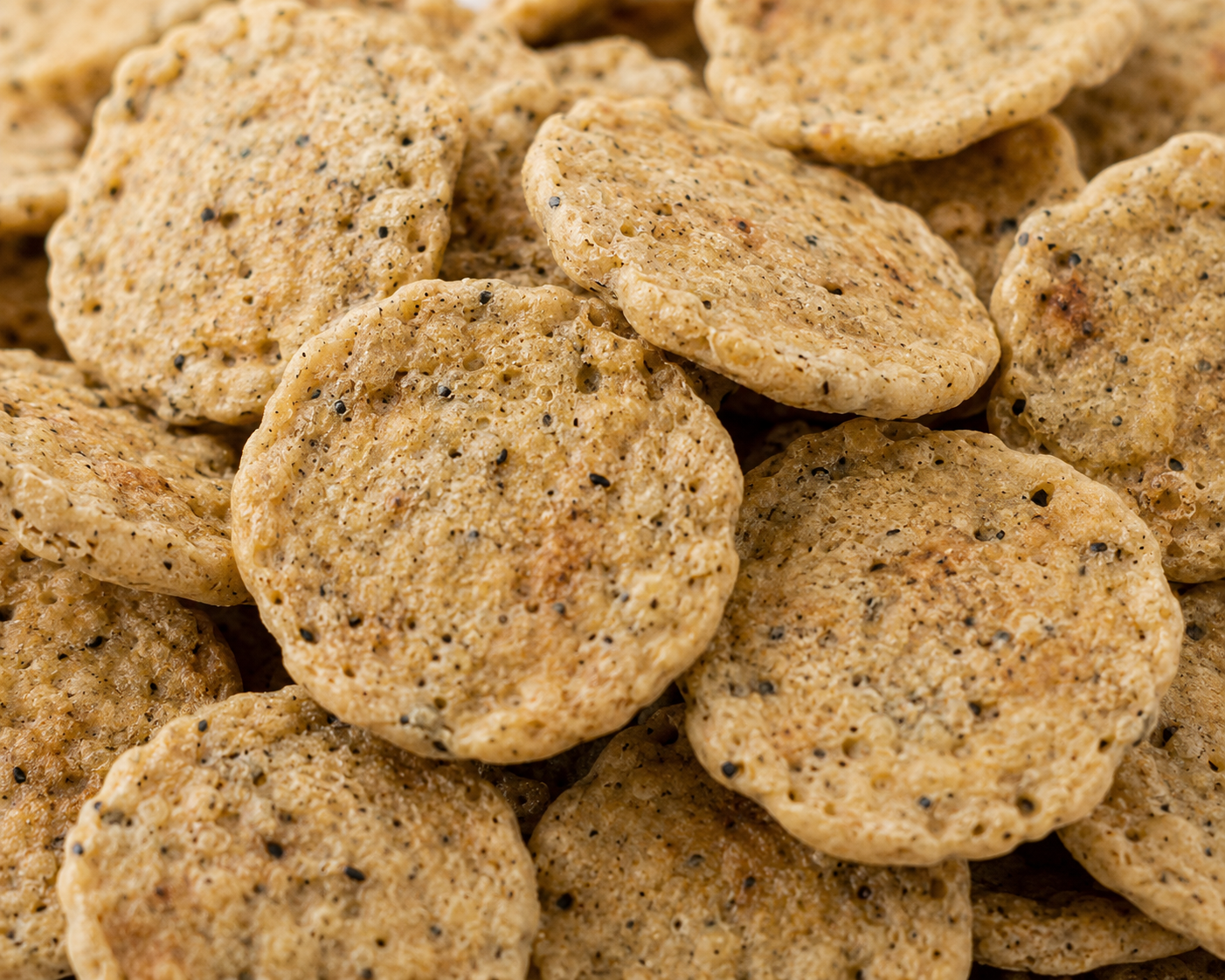 Close-up of a pile of round, brown cookies with specks.