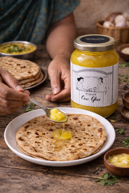 Person spreading ghee on a roti with a jar of Desi cow ghee in the background