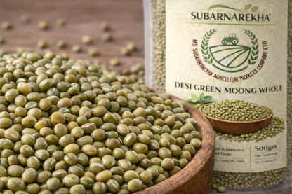 Green moong beans in a wooden closeup bowl with Subarnarekha packaging in the background.