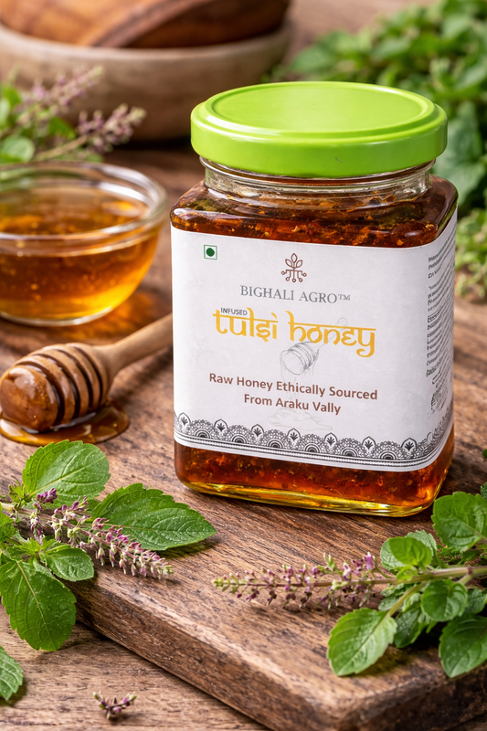 Jar of tulsi honey with a green lid on a wooden surface surrounded by herbs and a bowl of honey.