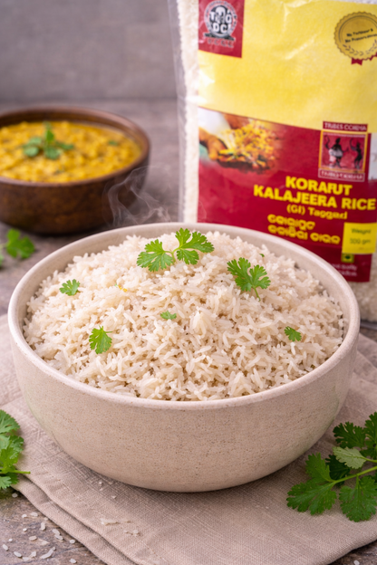 Bowl of rice with a package of Korarut Kalajeera Rice in the background.