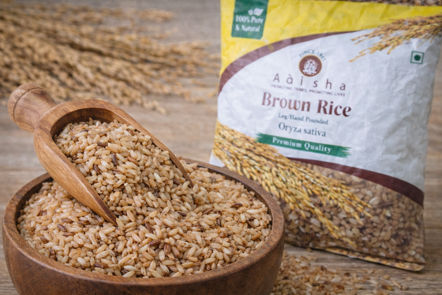 Brown rice in a wooden bowl with a scoop and Aasha Brown Rice packaging on a wooden surface.