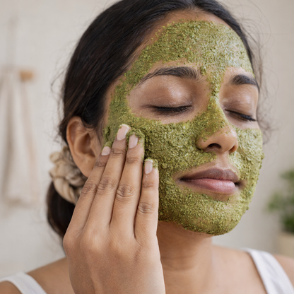 Woman applying a green facial mask to her face