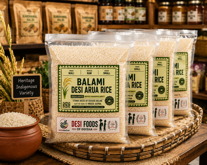 Four clear plastic bags of Balami Desi Aruna Rice displayed on a woven tray in a rustic shop setting.