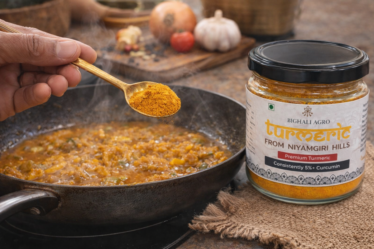 Person adding turmeric powder from a jar labeled 'Bighali Agro' into a pan with food.