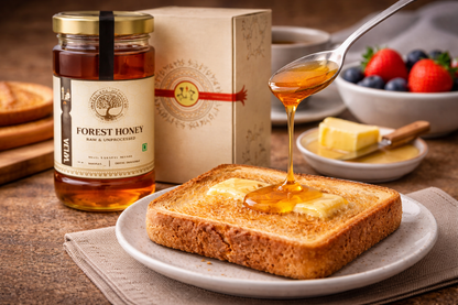 Jar of forest honey, toast with butter, and a spoonful of honey on a wooden table.