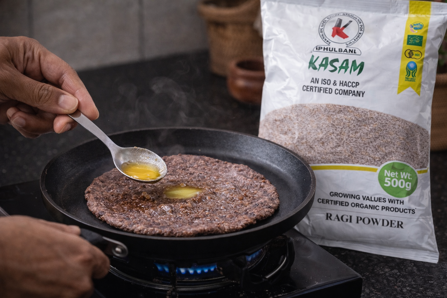 Person cooking a flatbread with egg on a pan next to a bag of Ragi powder.