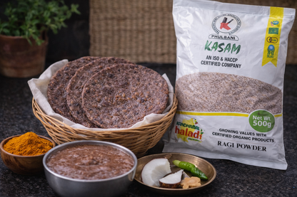 Ragi powder packaging with flatbreads, spices, and a bowl of chutney on a dark surface.