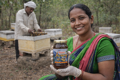 Woman holding a jar of honey in a beekeeping setting