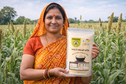 Woman holding a package of 'Desivog Multi Millet Atta' in a sorghum field.
