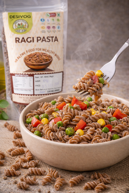 Ragi pasta in a bowl with a fork and Desivog Ragi Pasta packaging in the background.