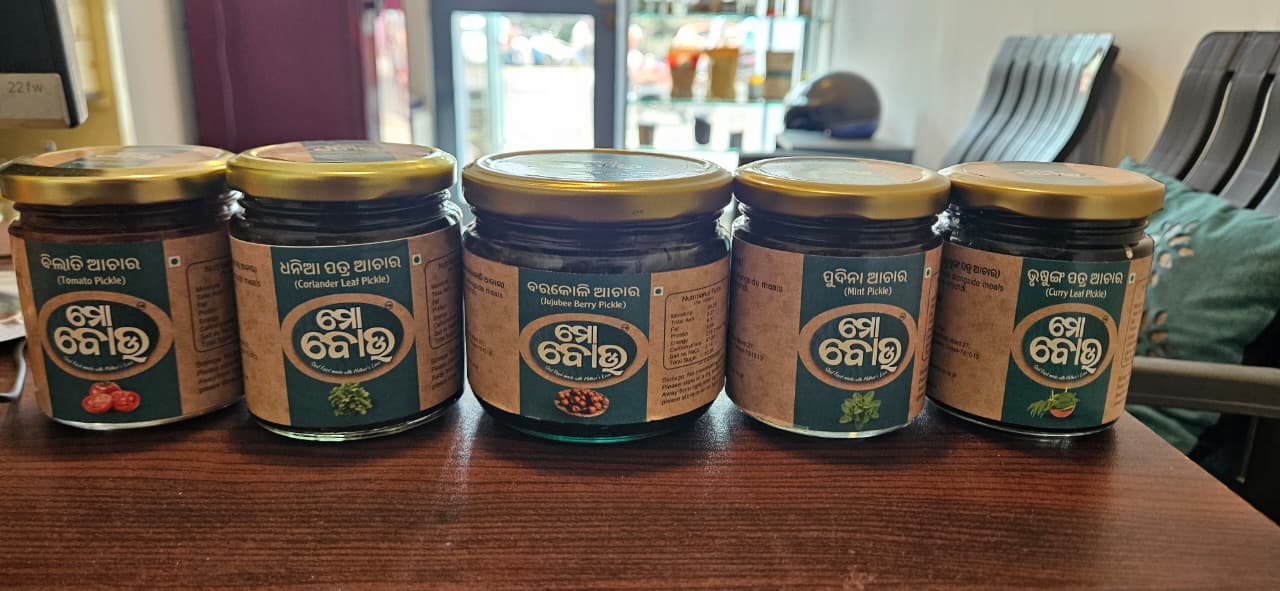 Five jars of a product with a brand label on a wooden surface.