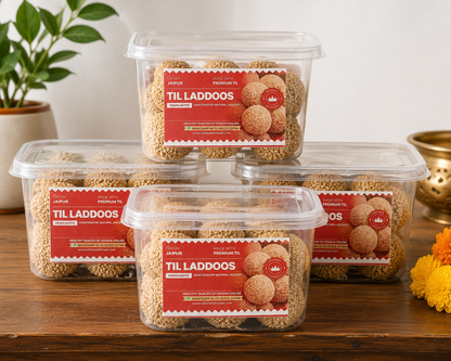Four containers of 'Til Laddoos' with red labels on a wooden surface.